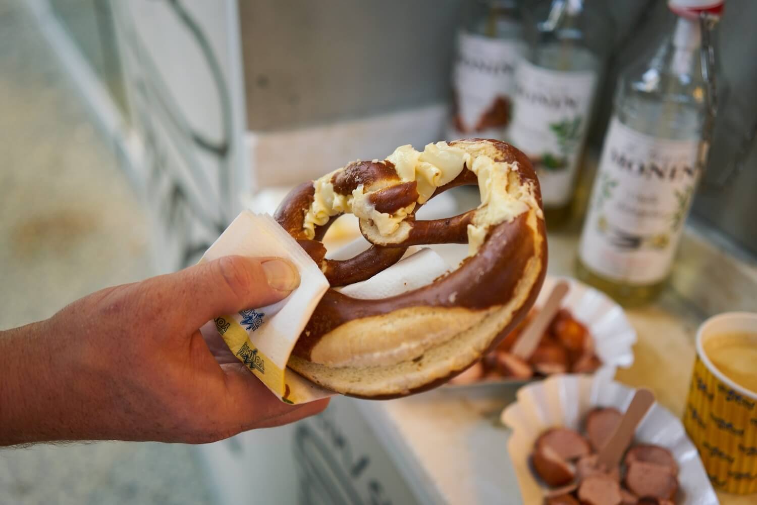 Hand holding a German pretzel with mustard during a private Berlin food tour in Kreuzberg.