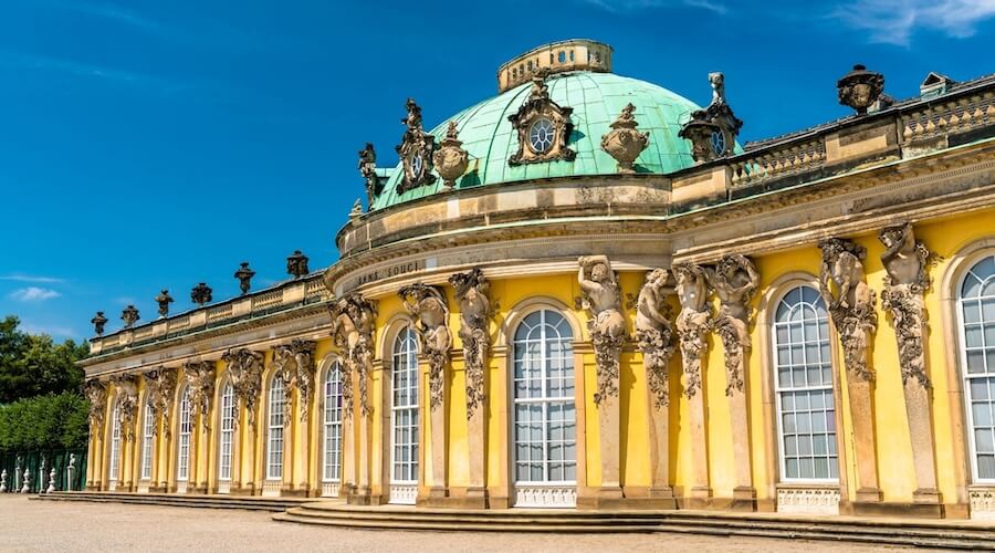Front façade of Sanssouci Palace in Potsdam with green dome and yellow walls, used as featured image for private Potsdam tours