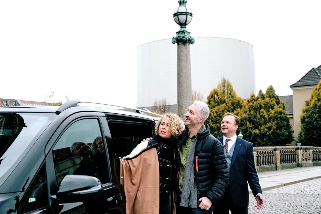 Travelers and private driver beside a tour vehicle during a Berlin shore excursion.