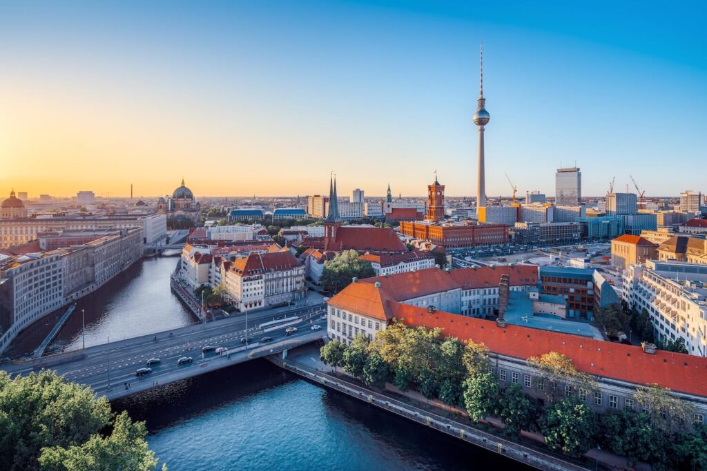 Panoramic Berlin skyline with the TV Tower, River Spree, and Museum Island at sunset.