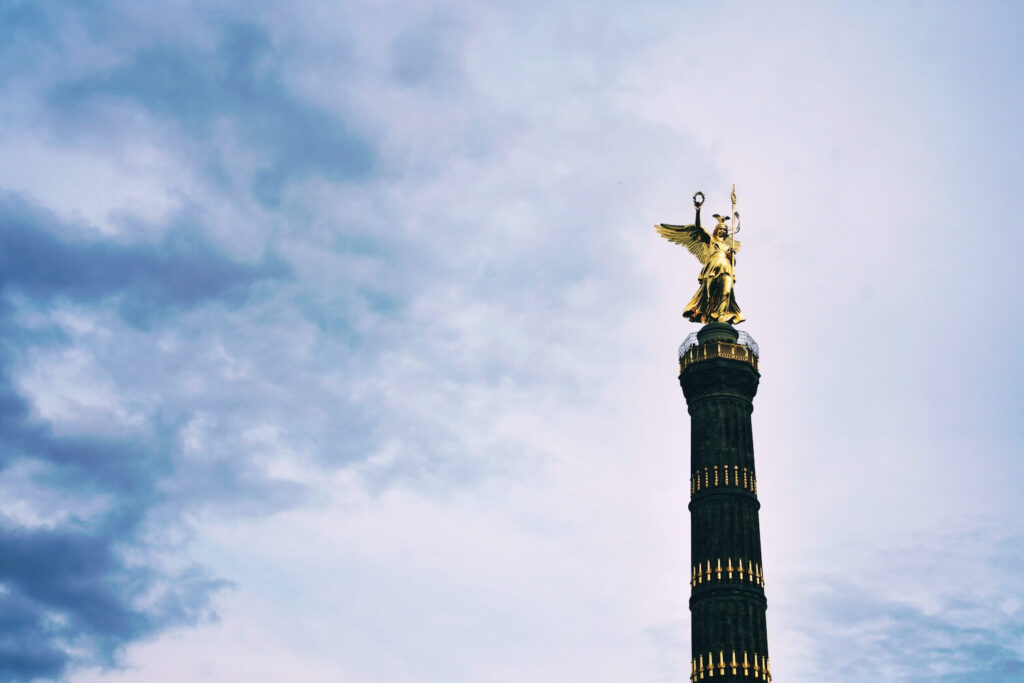 The golden Victoria statue atop Berlin’s Victory Column against a cloudy sky.