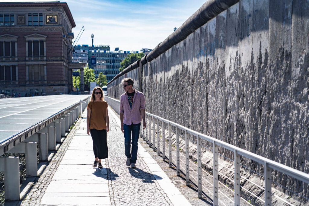 Travelers walking beside a preserved section of the Berlin Wall near the Topography of Terror in Berlin.
