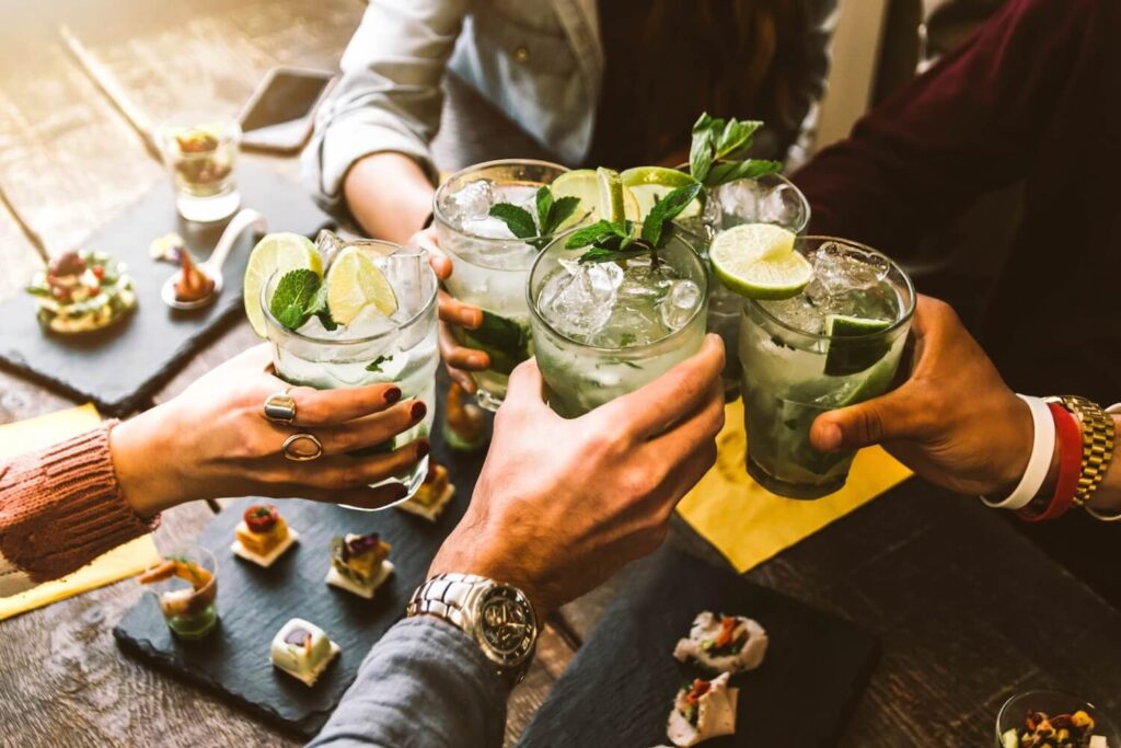 Guests raising cocktails with lime and mint alongside small snacks on a private Berlin cocktail tour.