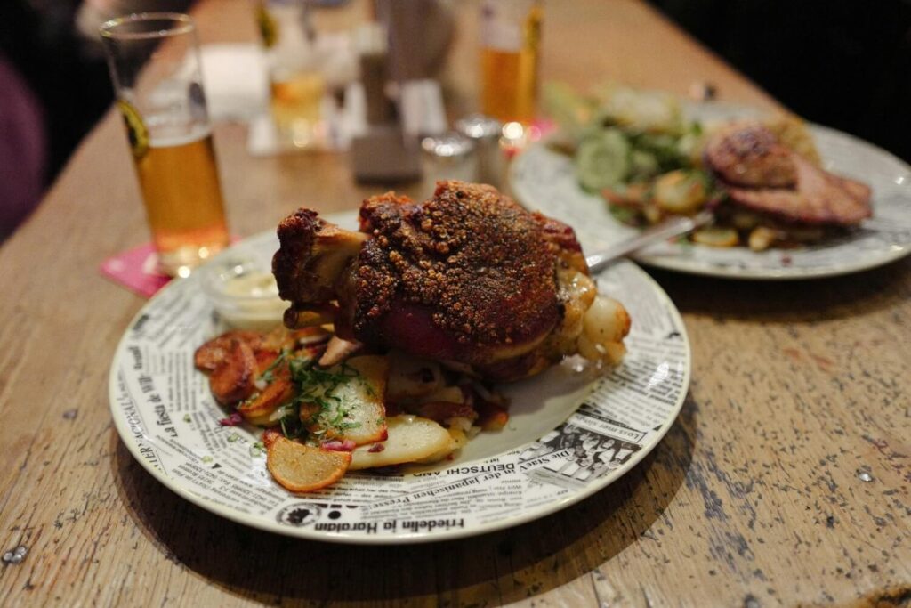 Traditional German pork knuckle with potatoes and beer, served in a casual Berlin restaurant.