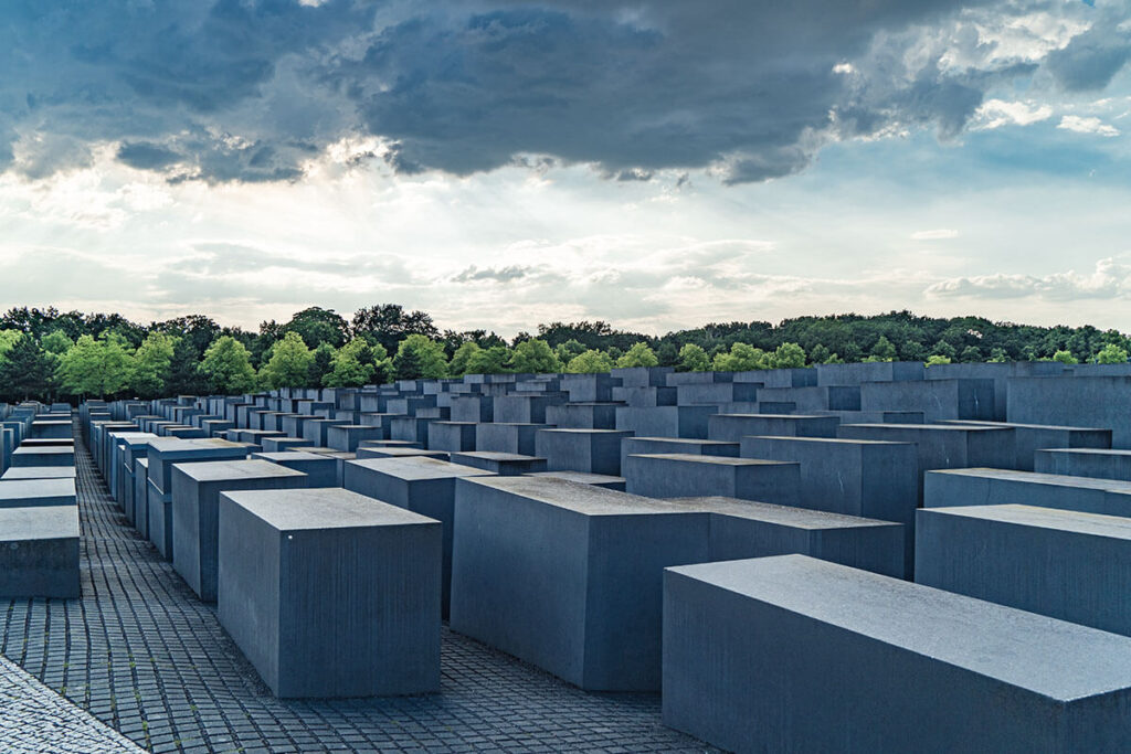 Concrete stelae at the Memorial to the Murdered Jews of Europe in Berlin under a dramatic sky.