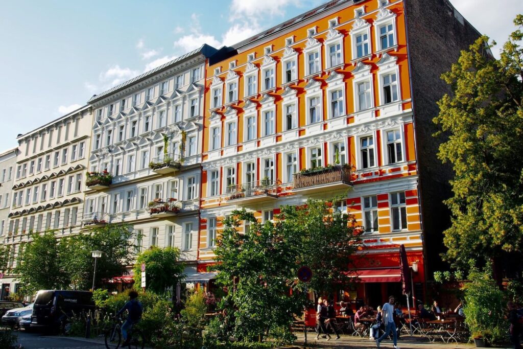 Colorful street with cafés and historic apartment buildings in Kreuzberg, Berlin.