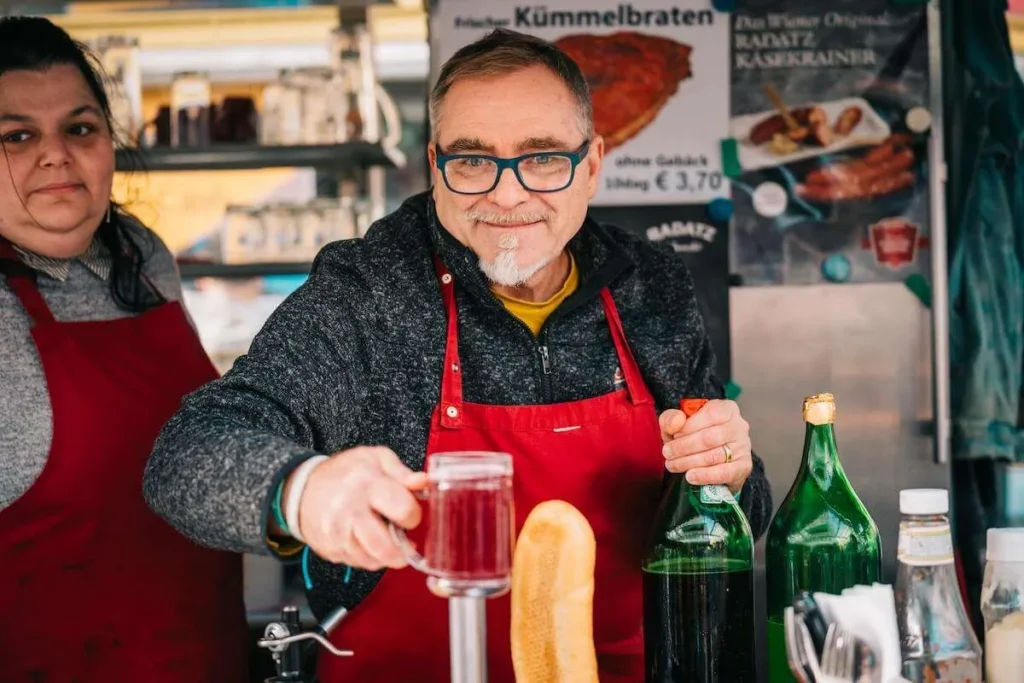 Market vendor serving a drink during a Vienna food tour stop