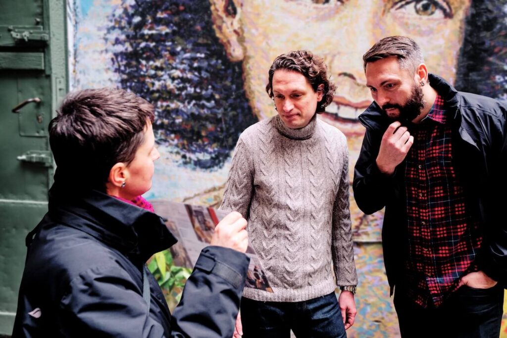 A Berlin guide uses historical images to explain the city’s past to two private tour guests.