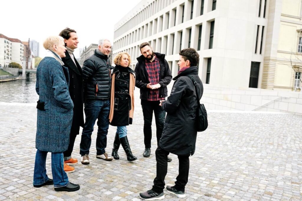 A small private tour group listening to a local guide in central Berlin.