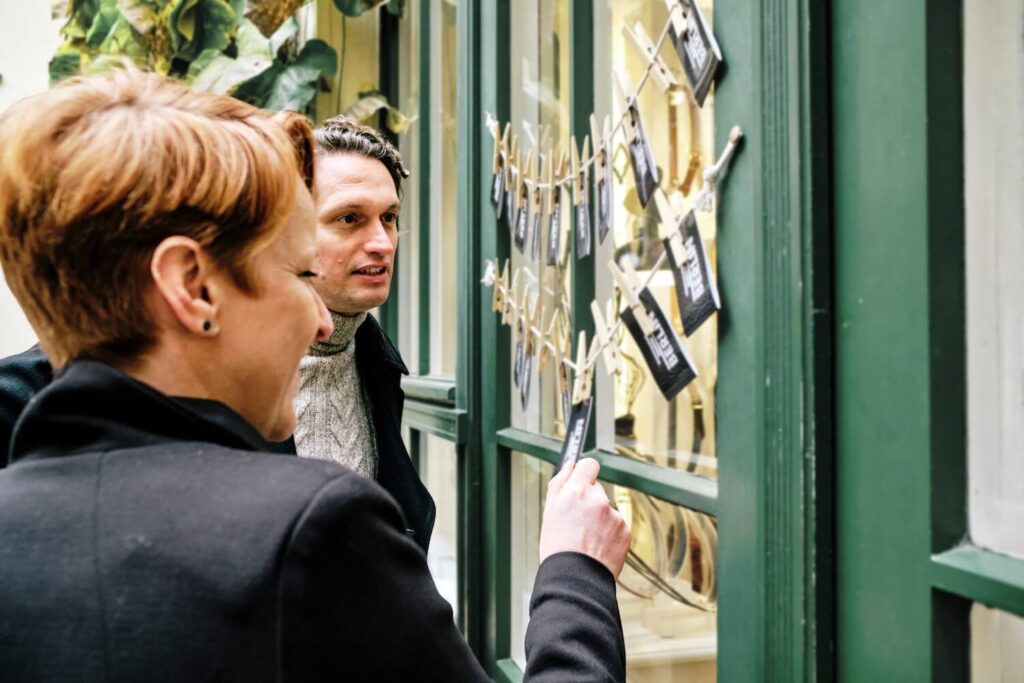 Two visitors examining historical photographs with a local guide in Berlin.