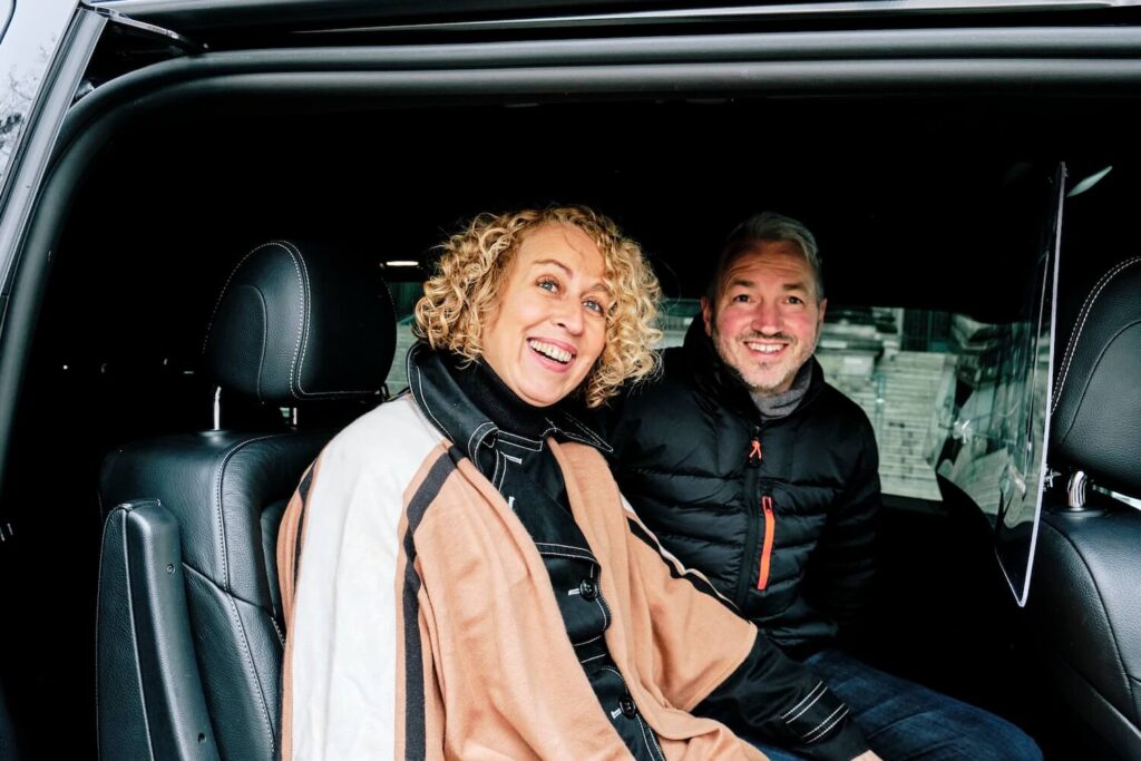 Two guests in the back of a private vehicle between stops on a Berlin family history tour