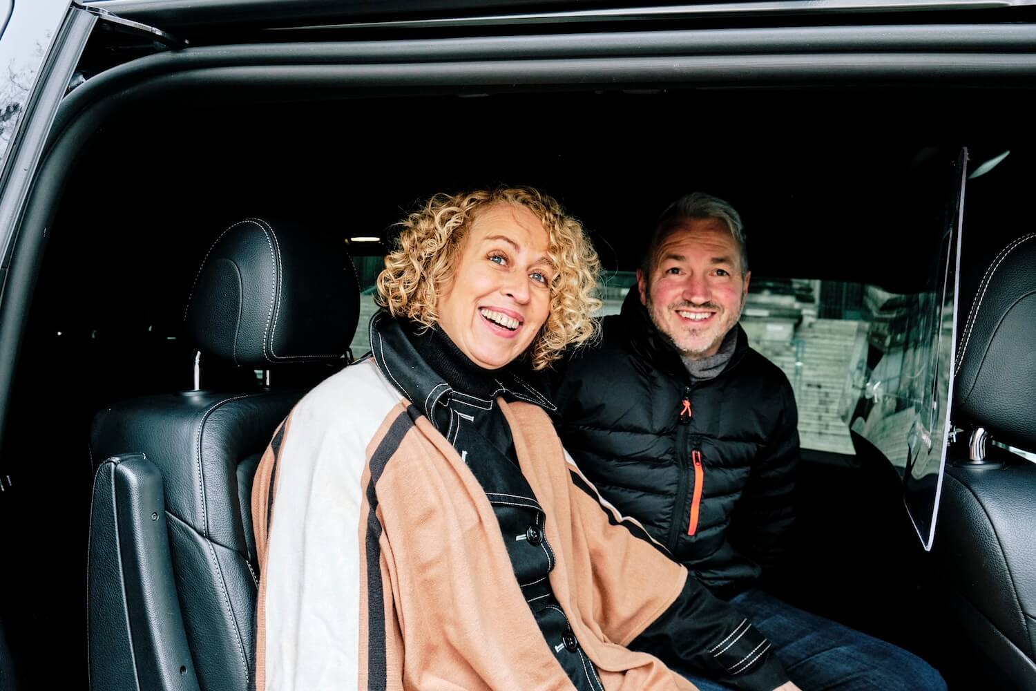 Zwei Gäste auf der Rückbank eines Privatwagens zwischen den Stationen einer Berliner Tour zur Familiengeschichte.